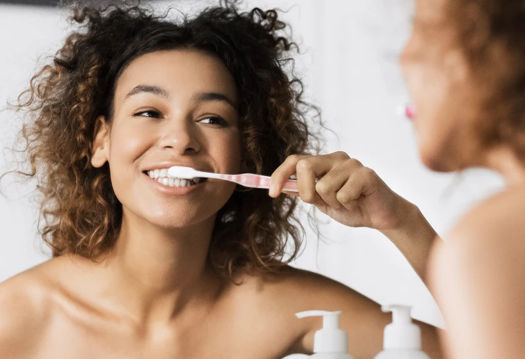 Jeune femme se brossant les dents pour une bonne hygiène bucco-dentaire après une restauration carieuse