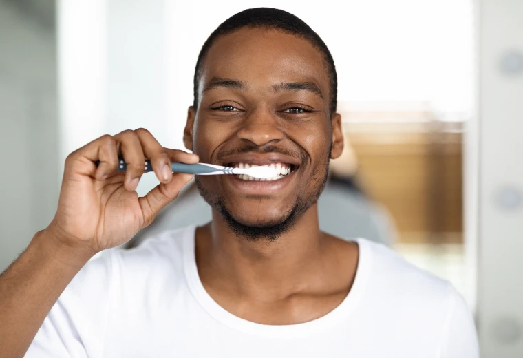 Homme souriant se brossant les dents avec une brosse à dents