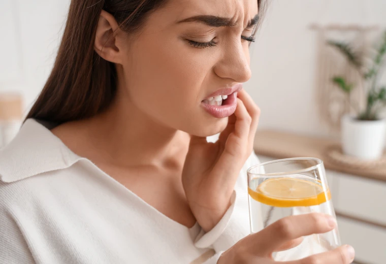 Femme souffrant de sensibilité dentaire en buvant une boisson froide